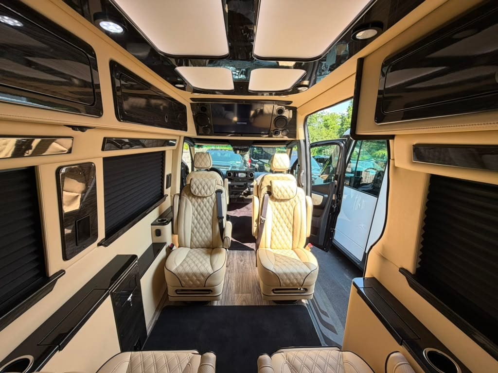 Mercedes-Benz Sprinter van interior with quilted leather captain's chairs, overhead skylights and a built-in entertainment screen
